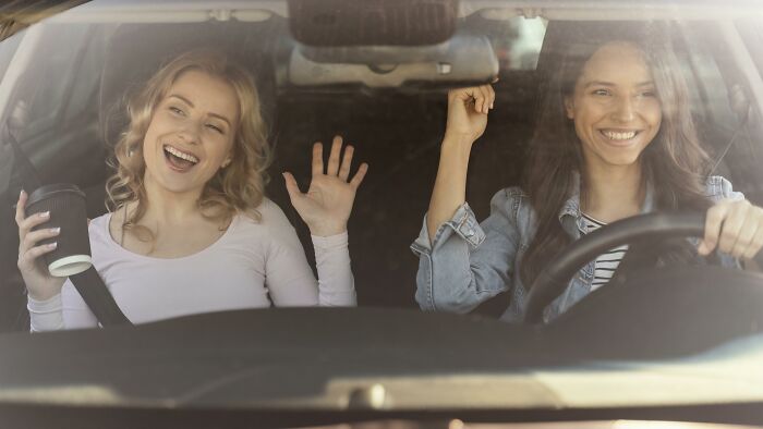 Two women smiling and enjoying a car ride, symbolizing moments before a painful friendship breakup final straw.