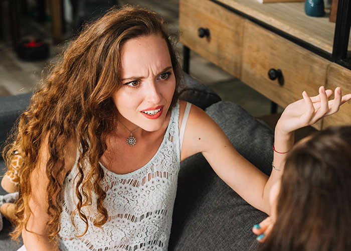 Woman with curly hair looking upset and arguing, calling out sister-in-law for pretending to have a food allergy.