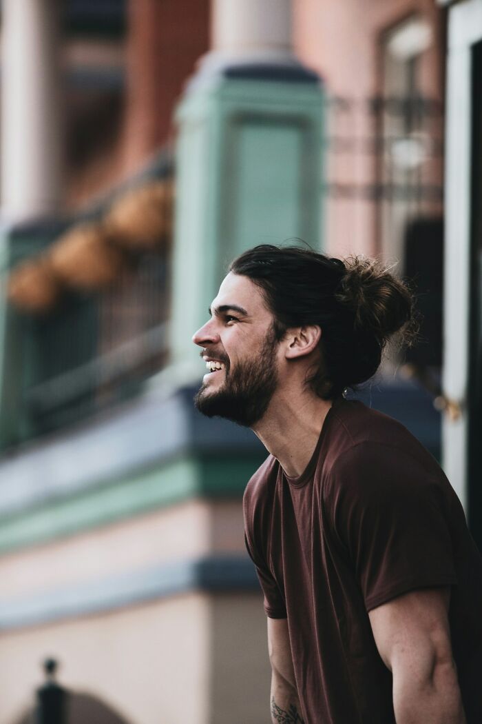 Young man with a beard laughing outdoors, capturing funny and clever moments in the heat of the moment conversation.