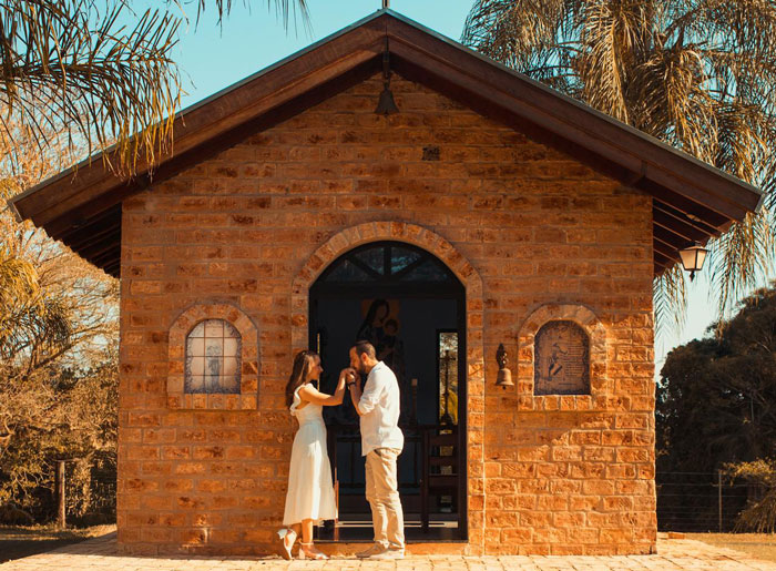 Couple standing outside a small brick chapel, symbolizing a small wedding and family relationship tension. Couple standing outside a small brick chapel, symbolizing a small wedding and family relationship tension.