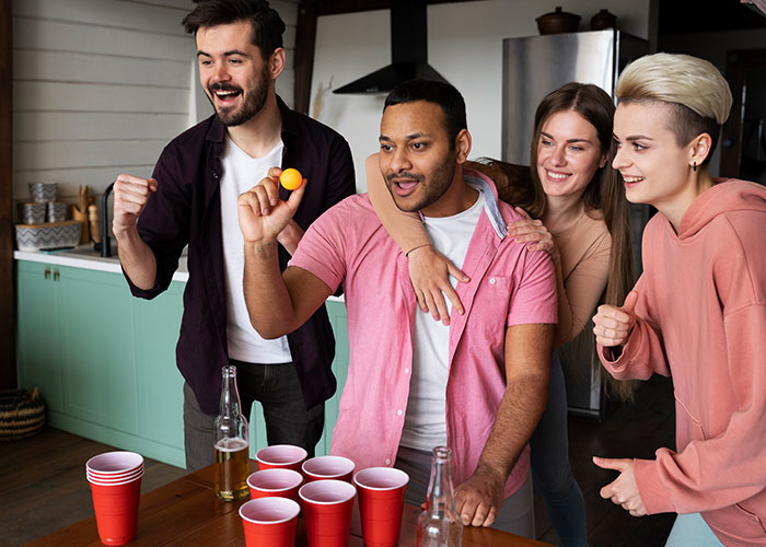Group of friends playing beer pong in kitchen, highlighting party scene related to boyfriend ditching newborn for over 18 hours.
