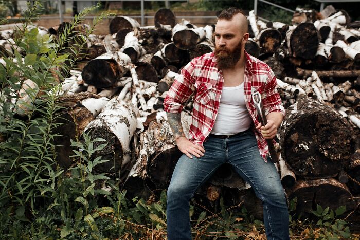 Man with tattoos and a beard sitting on logs outdoors, representing incredible minds who proved you don’t need a degree.