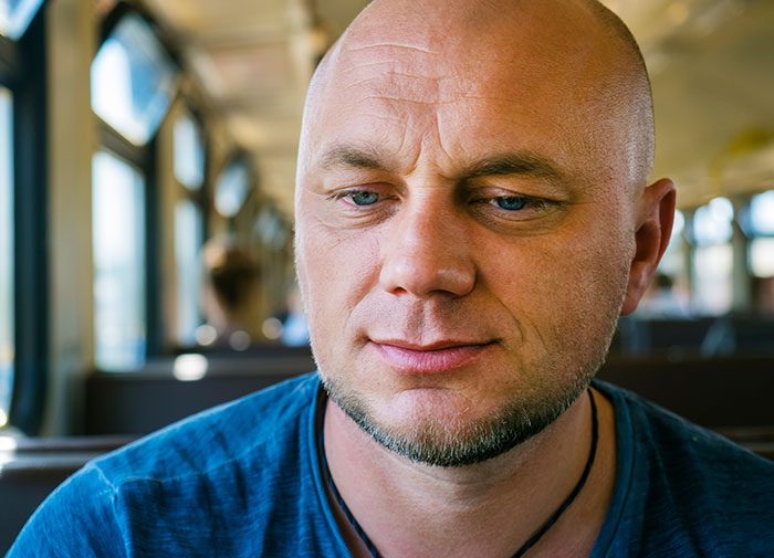 Close-up of a confident man with a slight smile illustrating mansplaining behavior in a casual environment.