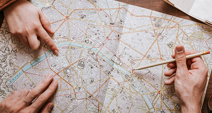 Two people pointing at locations on a detailed city map illustrating mansplained conversations with confidence.