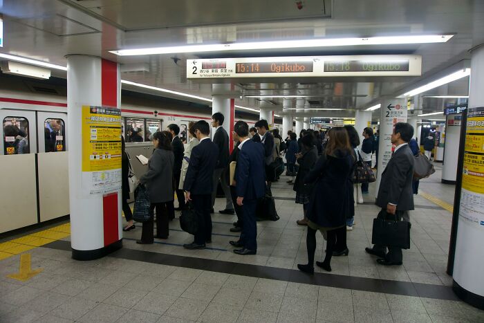 Commuters standing in line at a busy subway platform, illustrating moments of public entitlement and frustration.