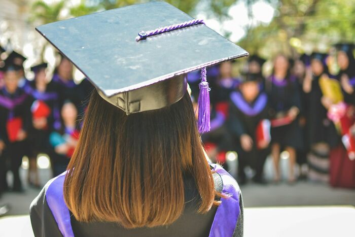 Graduate wearing a cap and gown at an outdoor ceremony, symbolizing new beginnings for a postal worker career.