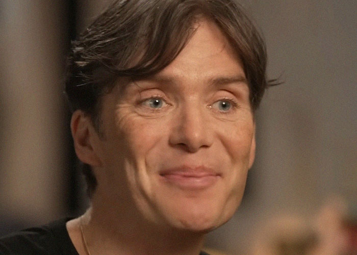 Close-up of a smiling man sharing stories about famous people they’ve met in a candid, informal setting.