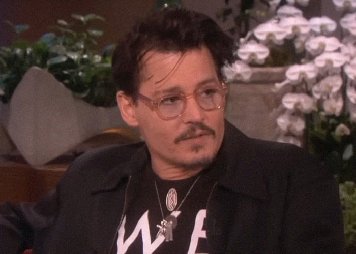 Actor in glasses sharing stories about meeting famous people in a casual interview setting with plants in the background.