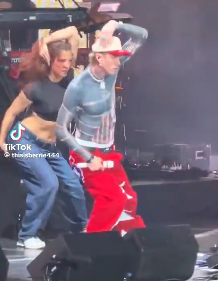 Machine Gun Kelly dancing on stage with a backup dancer in casual streetwear during a live performance. Machine Gun Kelly dancing on stage with a backup dancer in casual streetwear during a live performance.