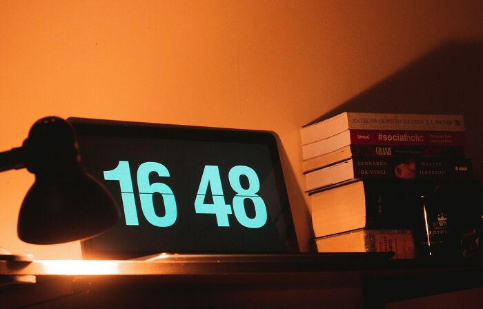 Digital clock displaying 16:48 on a desk with a lamp and a stack of books, illustrating small design mistakes.