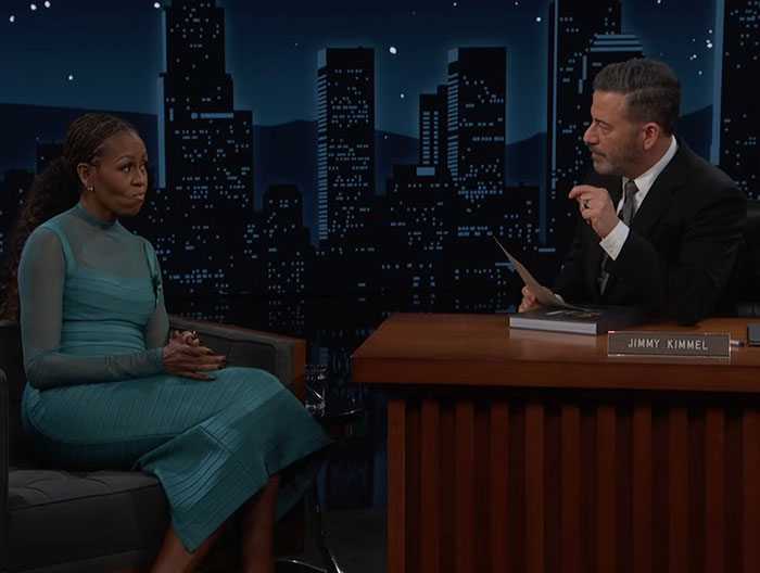 Michelle Obama in a teal dress during a late-night talk show interview discussing recent political controversies. Michelle Obama in a teal dress during a late-night talk show interview discussing recent political controversies.