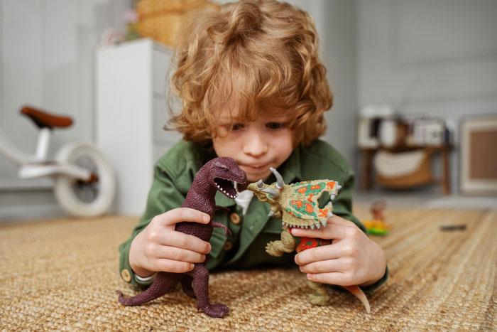 Young child playing on floor with dinosaur toys, capturing a playful moment related to grandma and Christmas gifts competition.