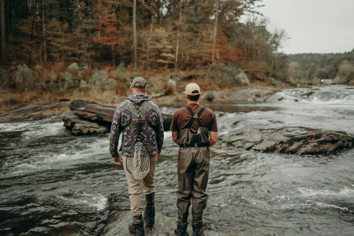 Two men fly fishing in a river, illustrating the idea of people trusting strangers online with secrets.