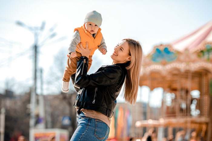 Mom holding baby at amusement park highlighting Disney dream with family and the cost of debt and guilt involved Mom holding baby at amusement park highlighting Disney dream with family and the cost of debt and guilt involved