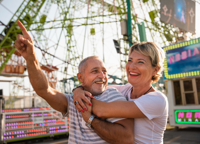 Smiling couple enjoying a theme park, highlighting the impact of a mom’s Disney dream causing family debt and guilt. Smiling couple enjoying a theme park, highlighting the impact of a mom’s Disney dream causing family debt and guilt.
