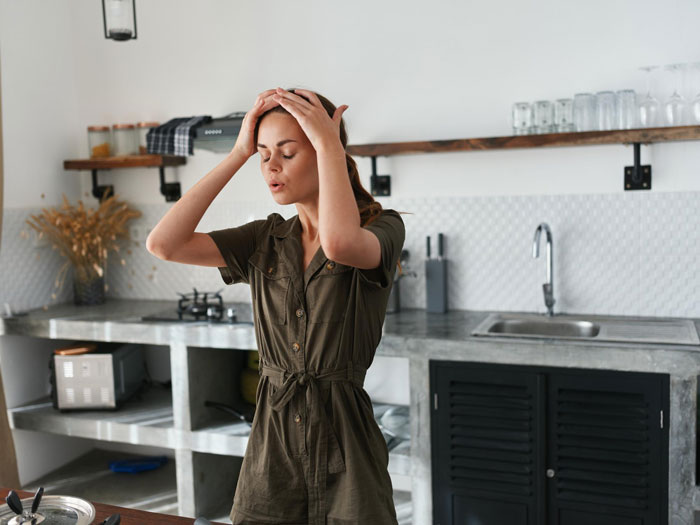 Woman in kitchen looking stressed, possibly preparing Christmas dinner for mom and daughter gathering.