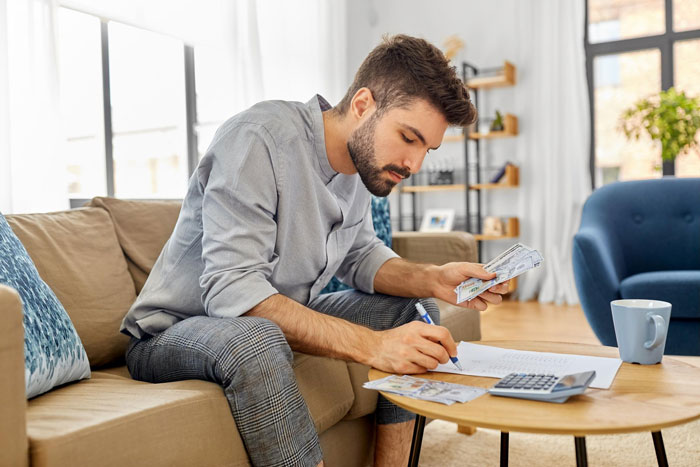 Man counting money and writing notes at a table, illustrating themes of cruel parents and refusal to help.