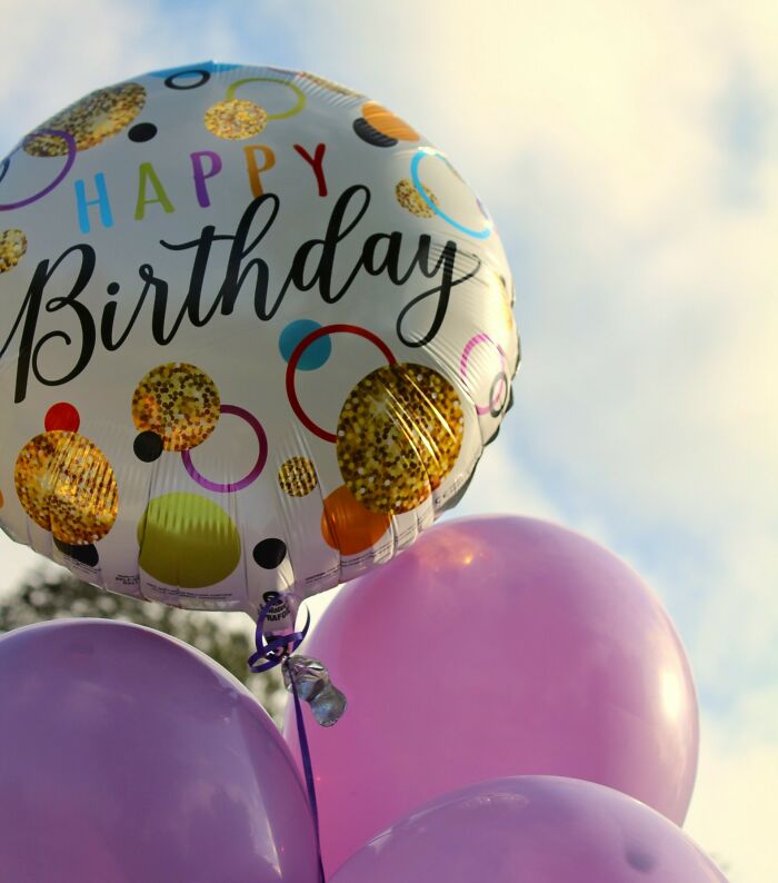 Balloons with a happy birthday message floating outdoors, contrasting with the unexpected scenes at funerals.