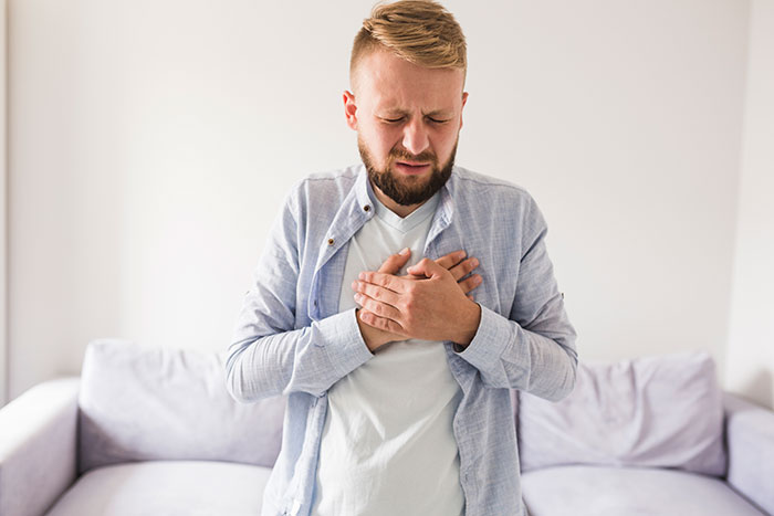 Man in casual clothes clutching his chest in pain, illustrating common wrong self-diagnoses shared by doctors.