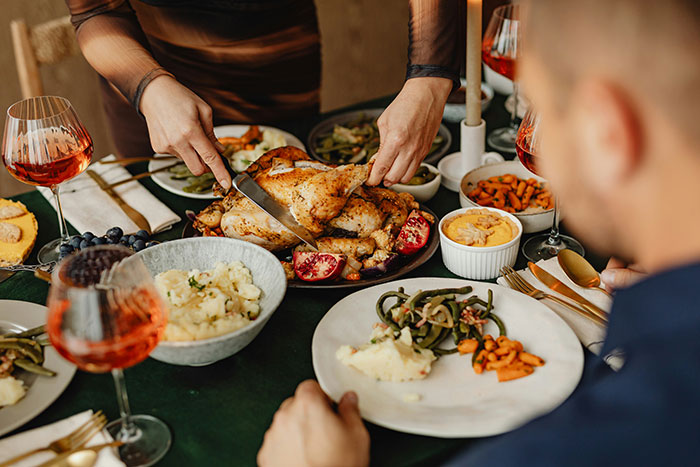 Couple hosting an expensive Thanksgiving dinner with roasted turkey and traditional side dishes on a festive table. Couple hosting an expensive Thanksgiving dinner with roasted turkey and traditional side dishes on a festive table.