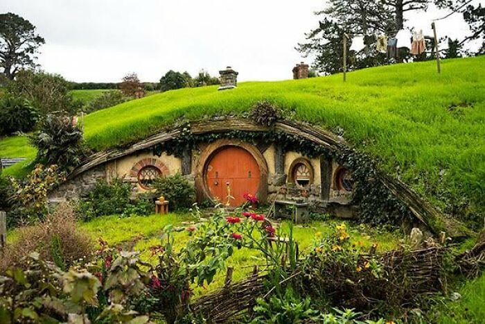 A picturesque hobbit house with a round door and lush greenery, one of the places from around the world that look AI generated.