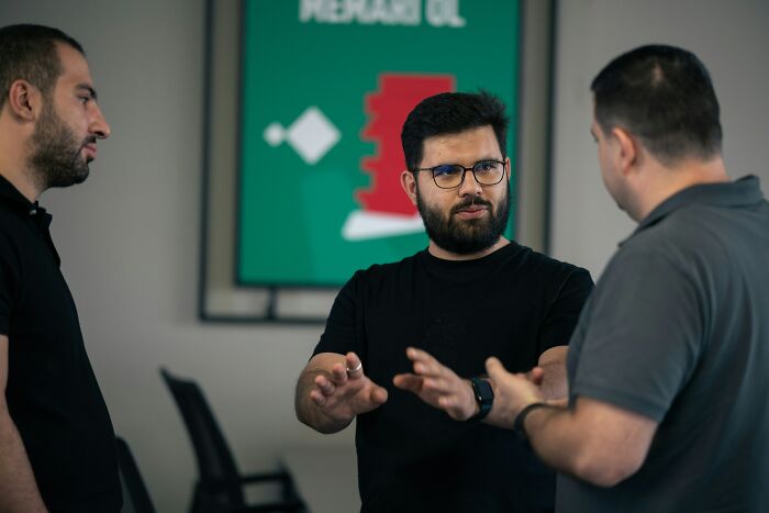 Three men engaged in a discussion, highlighting habits that can impact long-term mental and physical health.