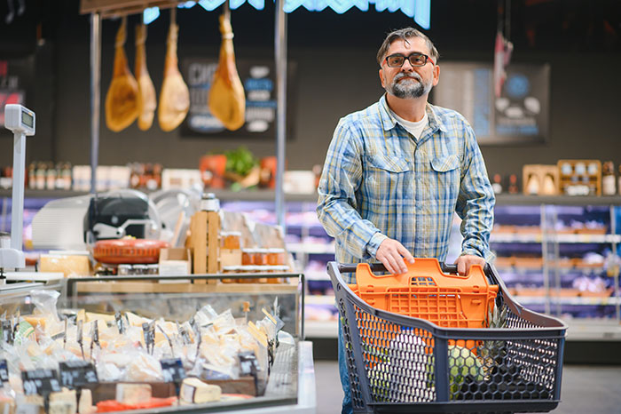 Man shopping in grocery store with cart, representing people from different countries denying popular myths foreigners believe.