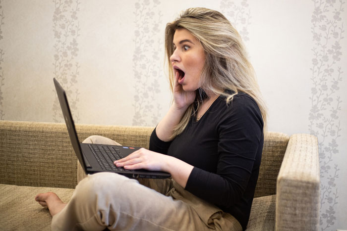Woman on couch shocked by laptop screen, illustrating karma for entitled nephew using credit card for games Woman on couch shocked by laptop screen, illustrating karma for entitled nephew using credit card for games
