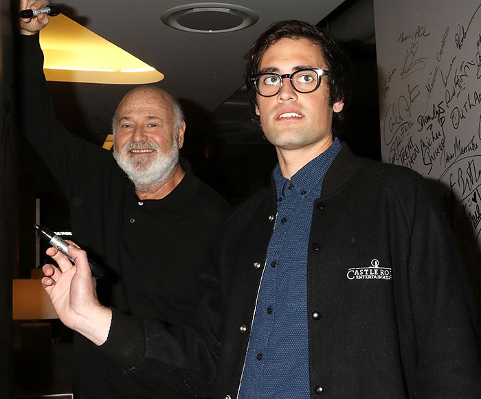 Rob Reiner and his son at an indoor event, with Reiner smiling and his son wearing glasses and a jacket.