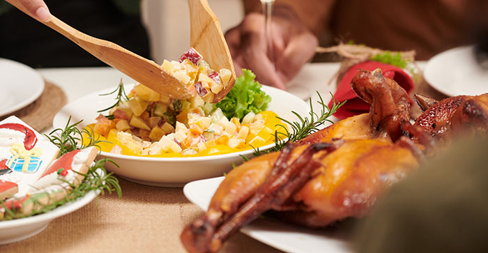 Hand serving traditional meat and potato salad on a holiday table with no vegan options Christmas Eve dinner.