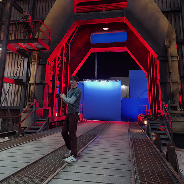 Noah Schnapp recreates a Stranger Things scene on set with red lighting and blue screen background at night. Noah Schnapp recreates a Stranger Things scene on set with red lighting and blue screen background at night.