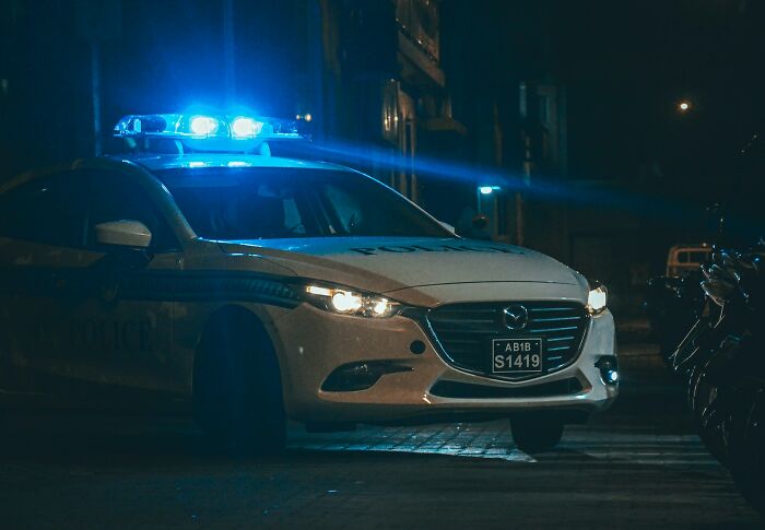 Police car with flashing blue lights at night, capturing a moment when people instinctively felt something was wrong.