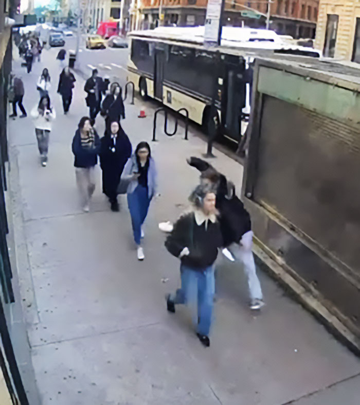 Pedestrians walking on a city sidewalk captured in viral video exposing serial creep after NYU shove incident.