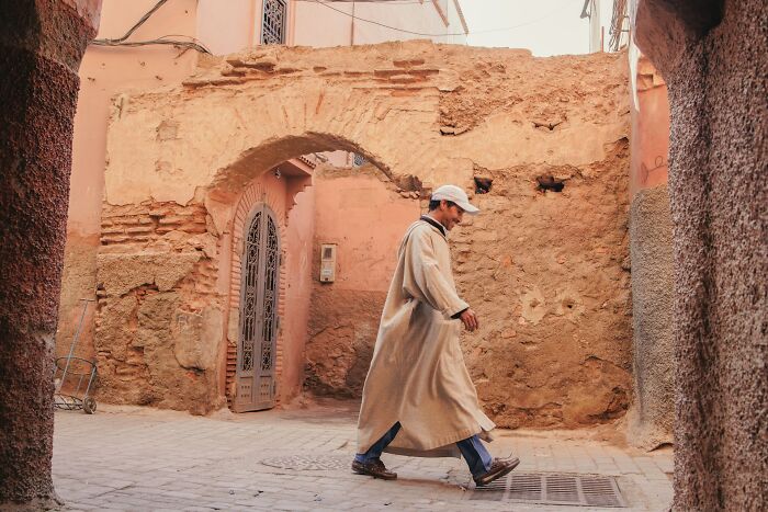 Man in traditional clothing walking past ancient stone archway in a historic area showcasing historical facts unknown until recently