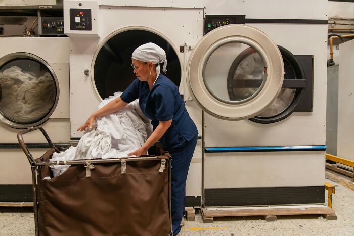 Laundry industry employee handling dirty linens in a commercial laundry facility revealing hidden industry truths.