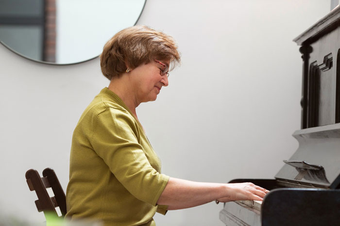 Woman playing an inherited piano at home after her parents donated the piano to church and she asked to take it back