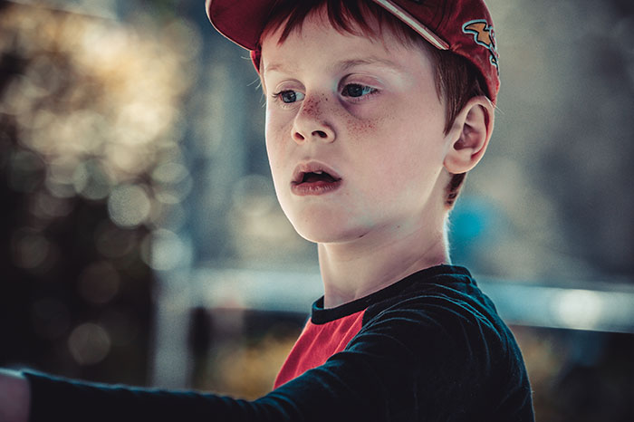 Young boy in a red cap looking distant, capturing a moment of a child displaying selfish and unloving behavior traits.