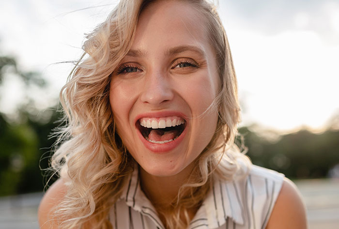Young woman with curly blonde hair laughing outdoors, illustrating selfish and unloving sociopath behavior in kids.