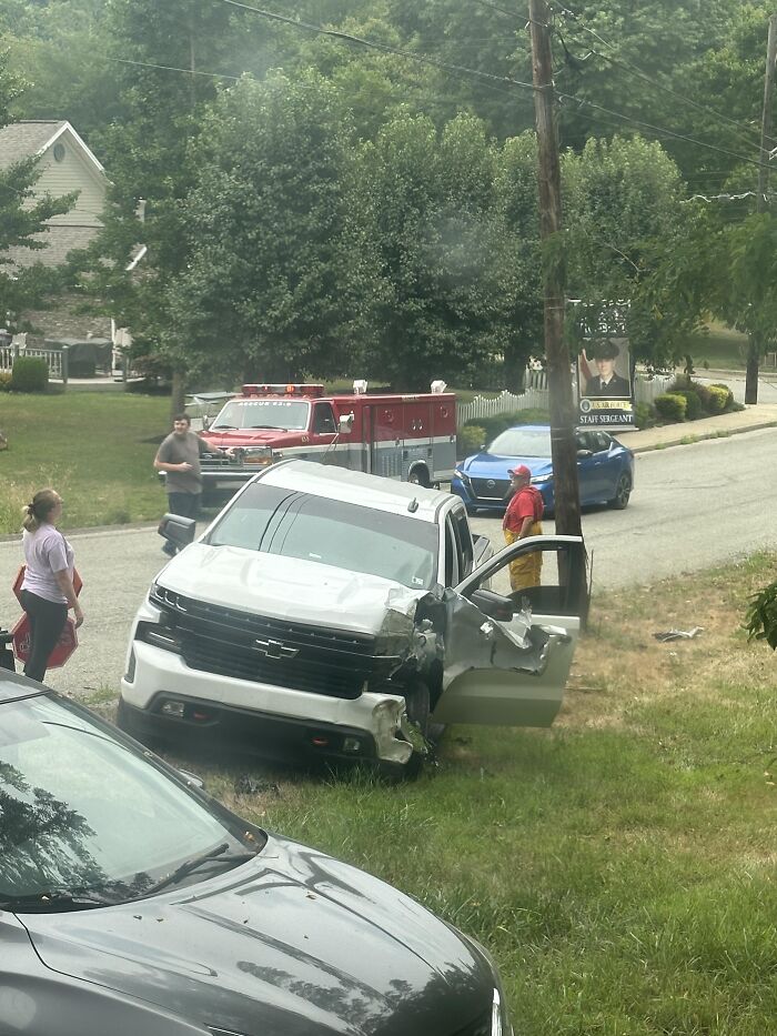 White pickup truck with severe front damage on a roadside, emergency responders and people nearby after a quick job quit incident.