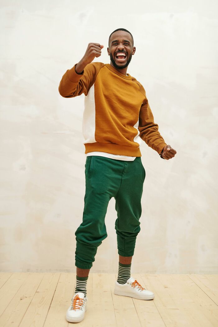 Man celebrating energetic fast job quit wearing casual outfit indoors on wooden floor background