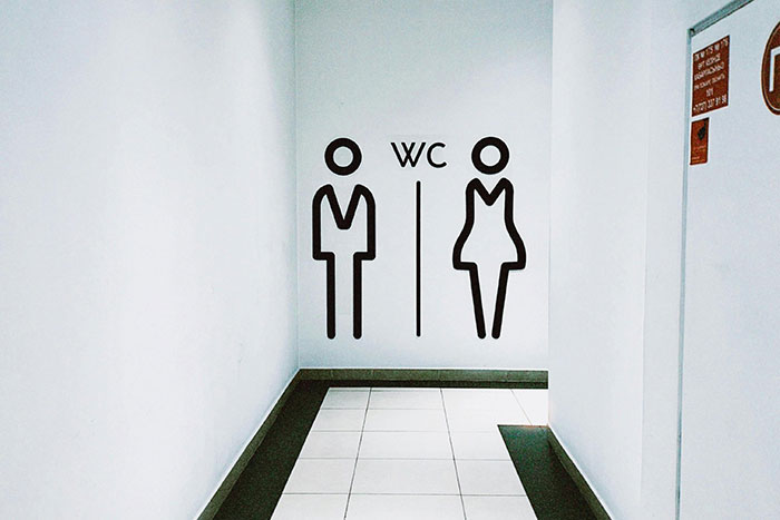 Minimalist restroom signs for men and women on a plain white wall, illustrating a legal shortcut idea for life easier.