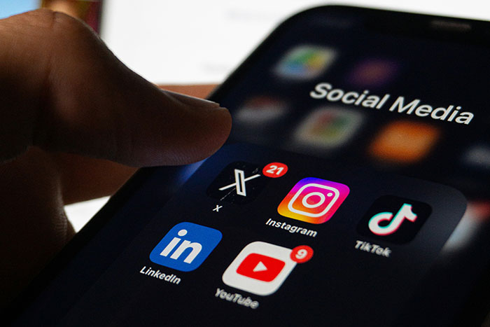 Finger about to tap social media apps on smartphone screen, illustrating legal shortcuts to make life easier.