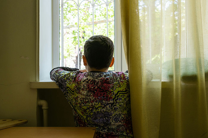 Child looking out a window during daytime, symbolizing the search for legal shortcuts to simplify life and ease challenges.