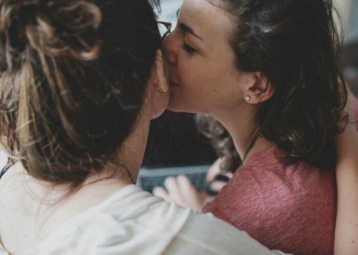 Two women embracing closely with one whispering to the other, hinting at a terrifying partner secret revealed.