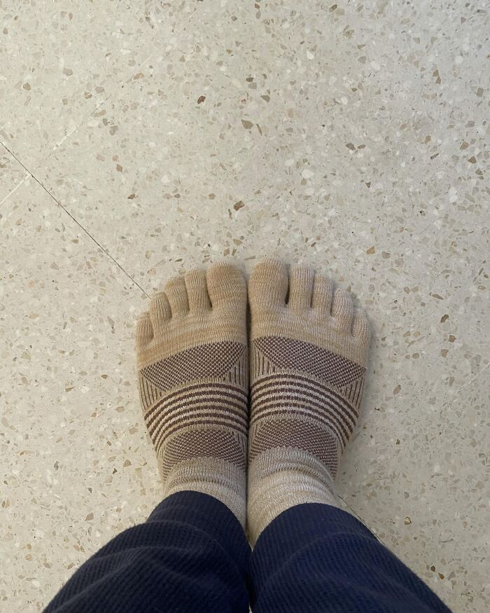 Close-up of feet wearing beige toe socks on speckled floor, illustrating unusual discoveries about partner experiences.