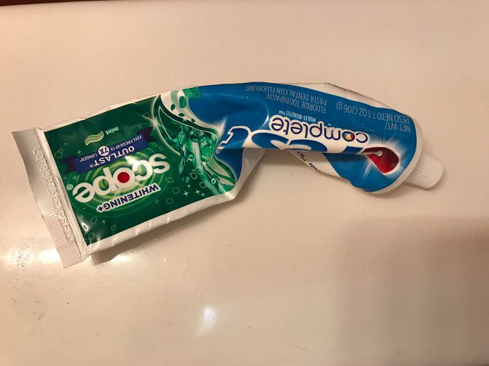Partially used toothpaste tube with two different brands combined, illustrating something terrifying about a partner.