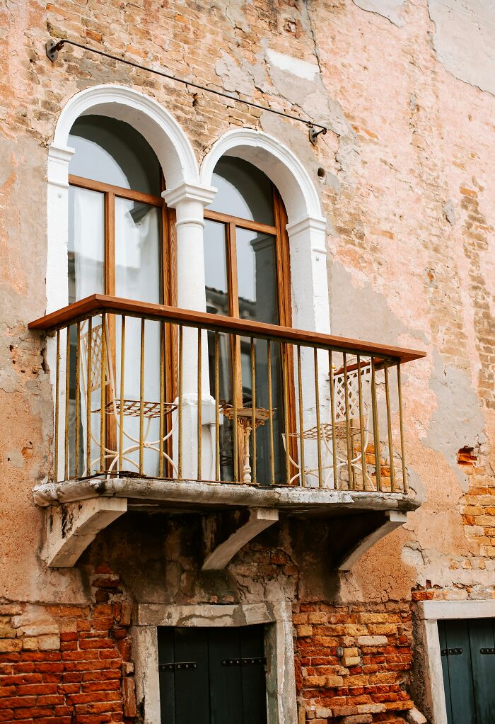 Old worn balcony with iron chairs on a weathered brick wall, evoking scary and eerie atmosphere people still talk about.