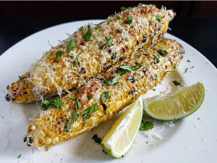 Grilled corn on the cob with cheese and herbs served with lime wedges, a dish foodies say didn’t need a gourmet upgrade.