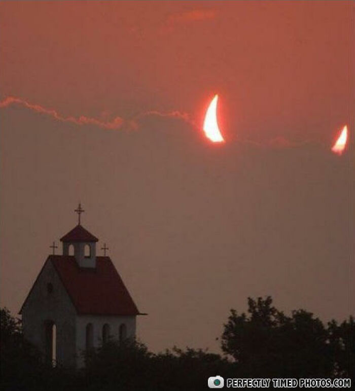 Silhouetted church with crosses at sunset featuring an impressive perfectly timed photo of a solar eclipse.