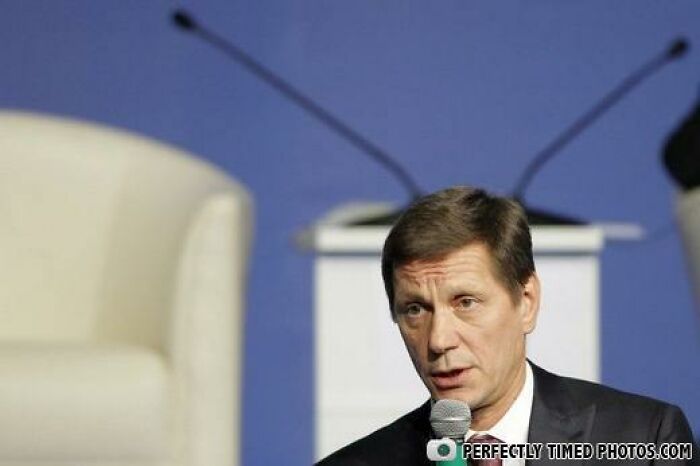 Man speaking into a microphone during a formal event, captured in a perfectly timed photo with clear focus.